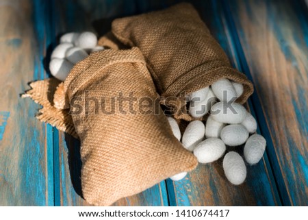white silk cocoon in sack on an old wood background