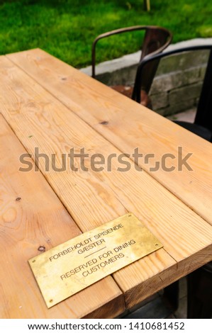 Sign on an outdoor table at a restaurant saying that it is reserved for dining customers in English and Danish