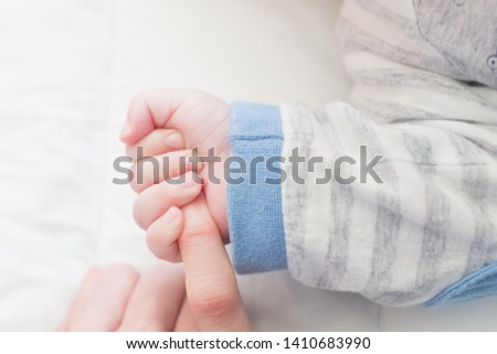 holding the finger of a father or mother tightly with the baby's hand on white blanket