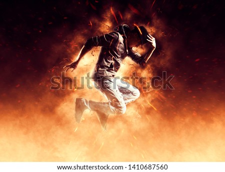 Young man break dancing on fire background