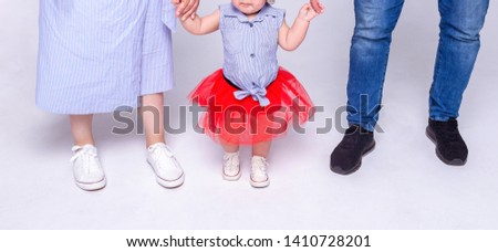 Young parents with little child on white background, holding child's hands, happy family