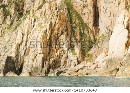 Nature creation in form of sandstone rock cliff formation great details in color texture with green grass in Binh Hung island, Khanh Hoa, Vietnam