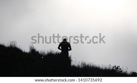 Silhouette of a person high up on on a mountain with mist Royalty-Free Stock Photo #1410735692
