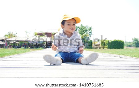 The Asian portrait side view of happy little boy sitting alone at the park, Kid happy face, child looking around outdoor children concept.