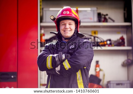 Image of happy male firefighter in helmet on background of fire truck