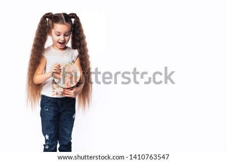 6-7 years girl in a good mood with beautiful hair holding present box and lookin inside with opened mouth. Happy and exited. White background. Copyspace