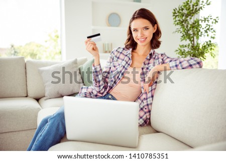 Close up photo beautiful she her lady bob notebook plastic wireless credit card hand arm recommend online shopping wear checkered plaid shirt jeans denim sit divan house loft living room indoors