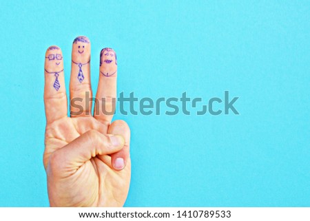 On the fingers of a twenty-year-old, three males were painted with pens - One of them wears a tie and glasses, the other a tie and the other finger was painted as a woman - concept to business fun