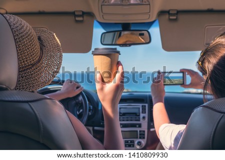 
Two girls traveling by car on the Italy. One of them taking picture on the mobile phone
