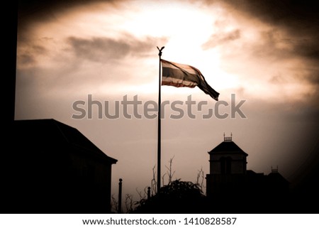 Thai flags against orange sunset sky during the summer with silhouette of buildings in the background
