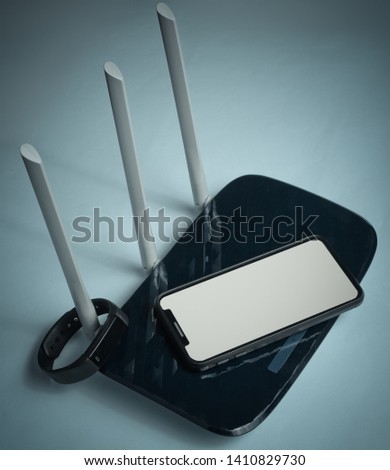 Wi-fi router, smartphone, fitness tracker on blue background. Gadgets for modern people. Copy space.