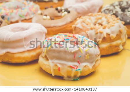 Colorful donut pattern on yellow background. Sweet food concept.