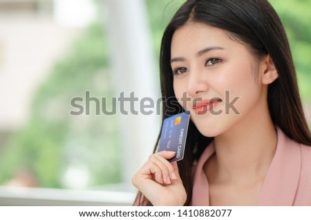beautiful young Asian woman smiling while using credit card for online shopping