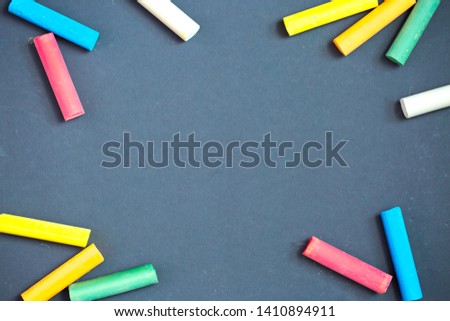 Colored chalk on a dark school board. The concept of children's creativity games, back to school. Blackboard with multicolored strokes from the chalk. Background texture with place for text, flat lay.