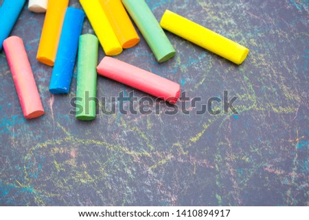 Colored chalk on a dark school board. The concept of children's creativity games, back to school. Blackboard with multicolored strokes from the chalk. Background texture with place for text, flat lay.