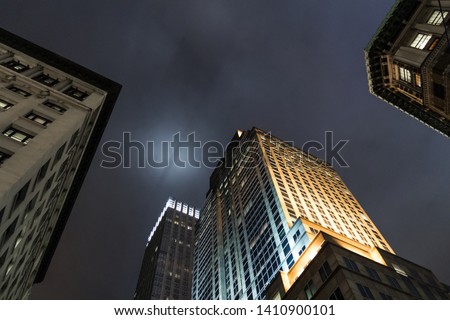 Manhattan skyscraper by night. A dark Knight Rises feeling. Beautiful light in the dark sky. Photo taken from a low-angle shot. Composition shot.