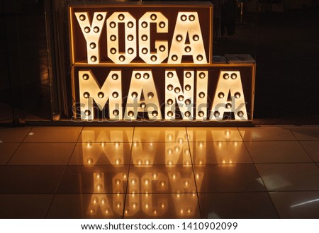 Shop Advertising. Yoga and yoga products. Illuminated advertising. Warm lamp light. Glowing letters.