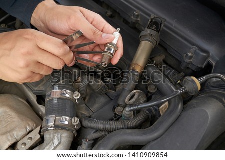 man check spark gap in the ignition plug with blade feeler gauge Royalty-Free Stock Photo #1410909854