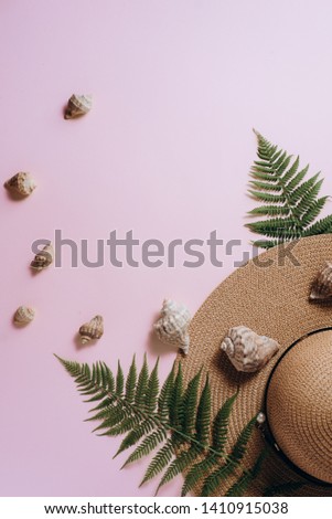 Minimal summer background. Tropical fern leaf branches, hat and seashell on pink background. Female fashion blog, social media. Flat lay, top view, copy space