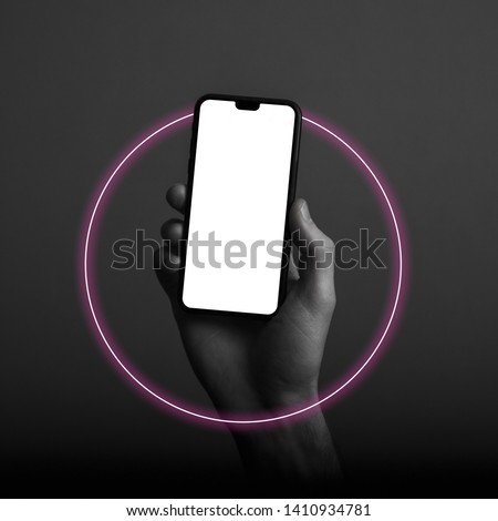 Hand holding modern smartphone with a blank white screen and neon light glow Royalty-Free Stock Photo #1410934781