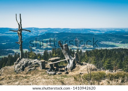 View from the top of a mountain into the valley with clouds in the blue sky and beautiful green trees and lots of rocks