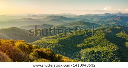 Layers of green mountains and hills in the haze during sunset. Sunset in the foothills of the Caucasus Mountains. View from Mount Akhun, Sochi, Russia.