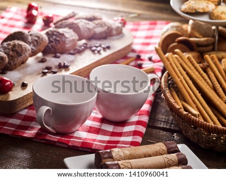 Oatmeal chocolate cookies with coffee grains and cherry, powdered sugar on kitchen cutting board with checkered fabric on wooden table in village style for picnic. Eat in small portions.
