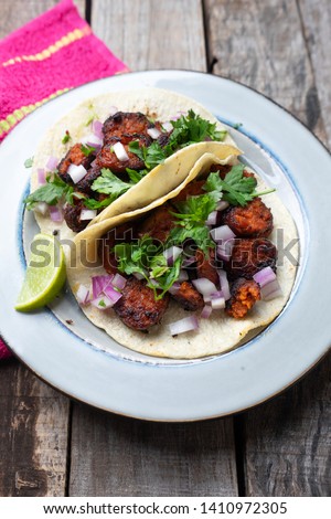 Mexican food: Delicious red chorizo tacos with corn tortillas on wooden background