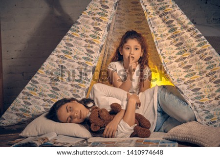 Mother and her daughter are in a teepee tent with some pillows. Happy family.