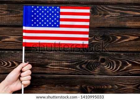 National day of USA concept with flag in hand on wooden background top view