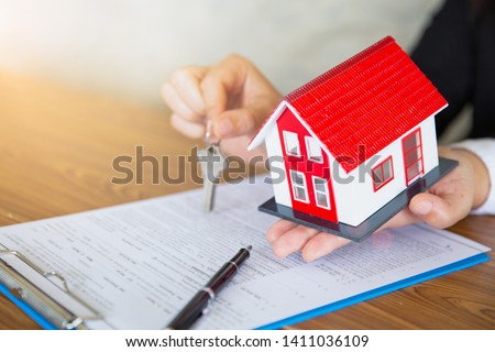 real estate agent holding house key to his client after signing contract agreement in office,concept for real estate, renting property