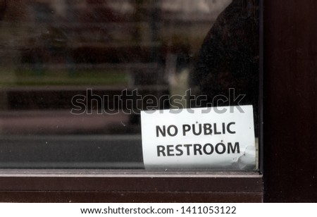 Abstract building window with no public restroom sign in daylight