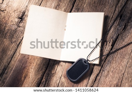 Rubber edge black military dog tag necklace with identity book on old wood background