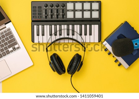 Headphones on music mixer, laptop and sound card on yellow background. The concept of workplace organization. Equipment for recording, communication and listening to music.