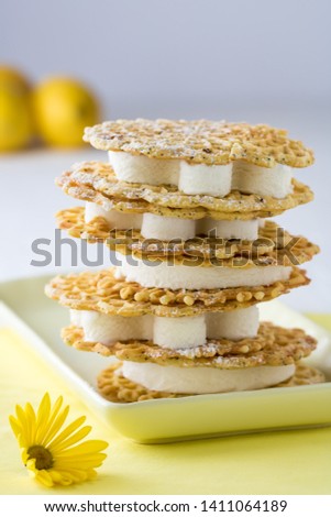 A stack of lemon poppyseed pizzelle ice cream sandwiches on a serving platter.