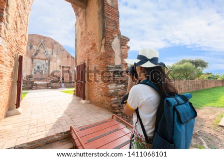 Backpacker tourists girl are taking pictures of old temples with cameras in Phra Nakhon Si Ayutthaya, Thailand.