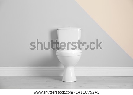 New toilet bowl near color wall indoors Royalty-Free Stock Photo #1411096241