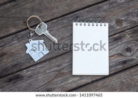 House key with home keyring and note paper in on old wood background, copy space