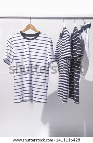Three striped fashion clothing and white shorts on hanger
