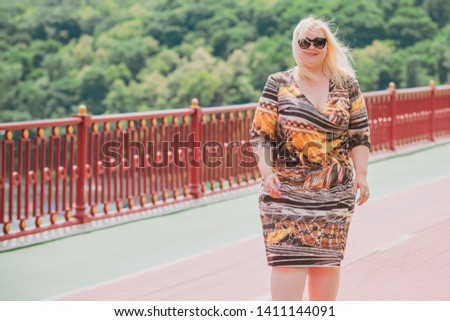 XXL woman walking on the city street at summer. Casual fashion, fashionable dress look. Plus size model. Happy overweight woman walking the city streets