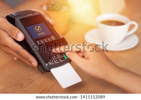 close up of hand entering credit card pin code for security password in credit card swipe machine at point of sale terminal in shop during shopping time Royalty-Free Stock Photo #1411152089