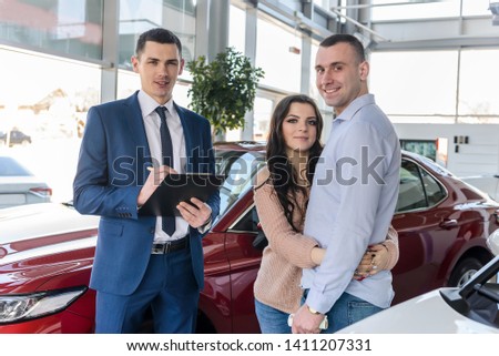 Young couple with salesman near new car signing contract