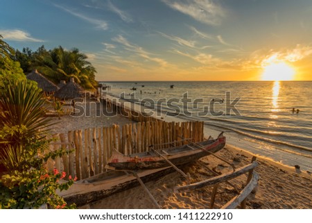 The beach of Ifaty, Mangily, near Toliara / Tulear South West Madagascar. Tropical sandy beach, thatched huts, exotic vegetation, traditional wooden fishing boat, people swimming and beautiful sky Royalty-Free Stock Photo #1411222910
