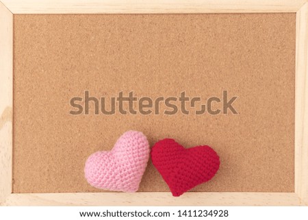 Classical plain brown cork board with red and pink knitting hearts at bottom of frame. Free copy space for text. Empty board background. Love photo concept.
