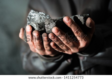 Coal mining : coal miner in the man hands of coal background. Picture idea about coal mining or energy source, environment protection. Industrial coals. Volcanic rock. 