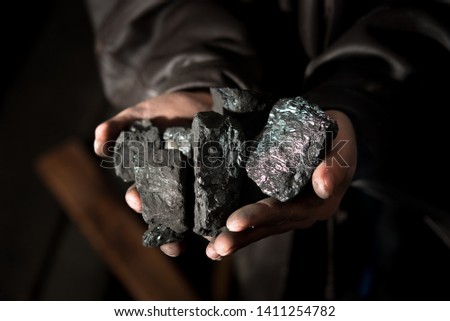 Coal mining : coal miner in the man hands of coal background. Picture idea about coal mining or energy source, environment protection. Industrial coals. Volcanic rock. 