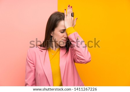 Young woman with pink suit over colorful background having doubts with confuse face expression