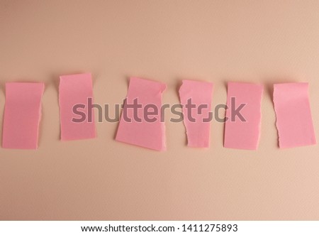 pink paper stickers pasted on the wall and torn in half on a peach background