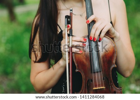 beautiful girl holding a violin in her hands. violinist in the forest