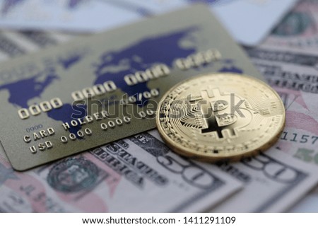 Gold coin bitcoin closeup lie on table with dollar paper and credit card aganist table background. Cryptocurrency exchange concept.